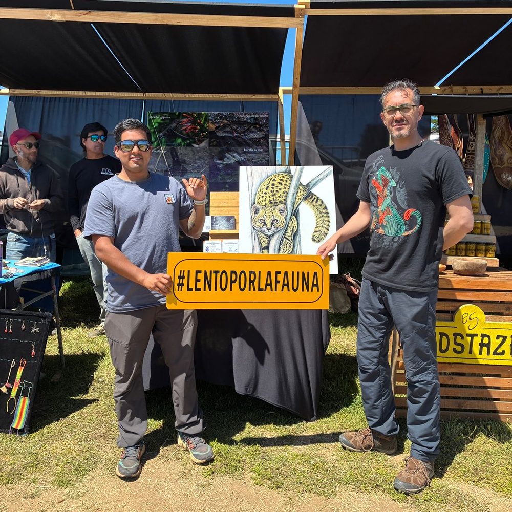 Two members of Fundación Pichilemu Wild holding a yellow sign with the hashtag #LentoPorLaFauna at a campaign stand.